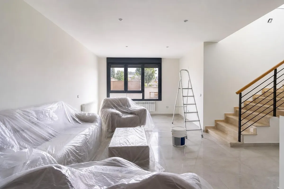 Salón de una casa en Utebo con los muebles protegidos durante el pintado